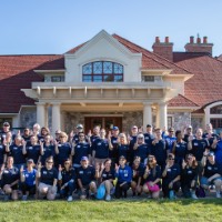 Group of GVSU Alumni Move in day volunteers take a group picture in front of Alumni House and Visitors Center and anchor up